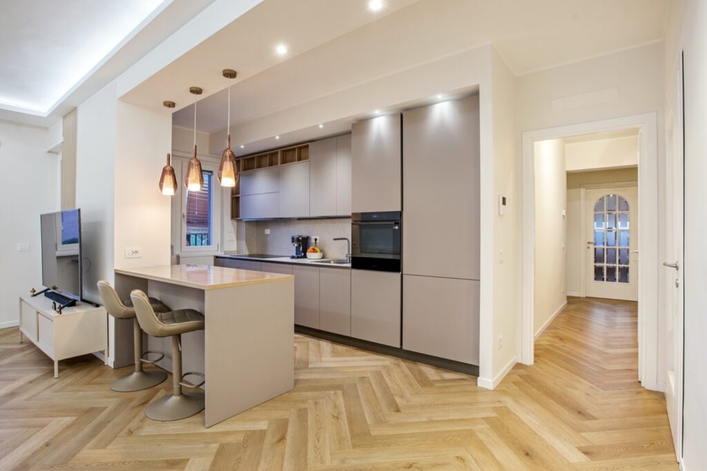 Cucina open con isola, parquet a spina e lampade in rame in appartamento ristrutturato a Roma — I Ristrutturatori
